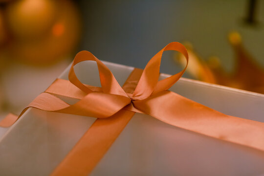 Elegant gift box wrapped with a beautiful orange satin ribbon and bow, creating a warm festive and celebratory atmosphere. Perfect for gift giving, holidays, birthdays, special occasions