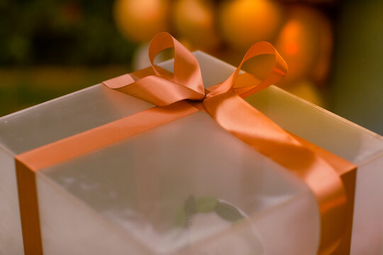 Elegant gift box wrapped with a beautiful orange satin ribbon and bow, creating a warm festive and celebratory atmosphere. Perfect for gift giving, holidays, birthdays, special occasions