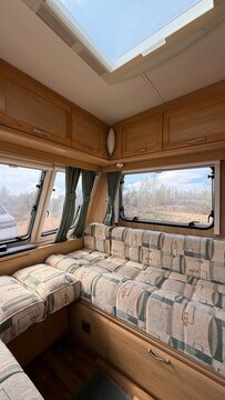 Comfortable caravan upholstery seating area with large windows inside a cozy modern camper