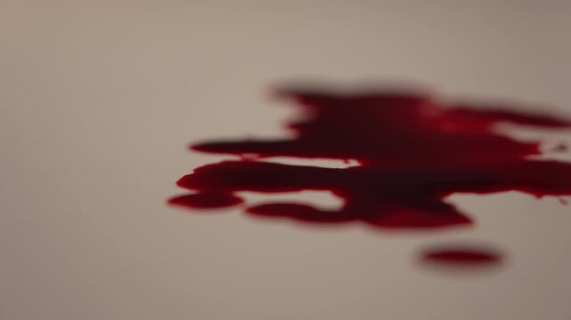 Macro side view of continuous blood dripping and flowing in slow motion, intense dramatic urgency for horror, slasher