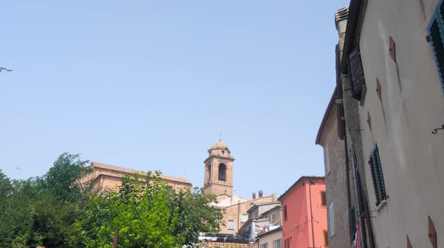 Inquadratura dal basso degli edifici storici e del campanile in mattoni nel borgo di Mondaino, turismo in Emilia-Romagna