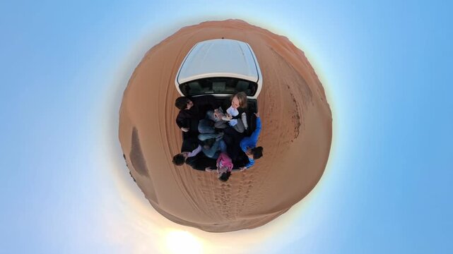 Aerial tiny-planet view of people seated in a pickup truck bed on circular desert dunes at sunset