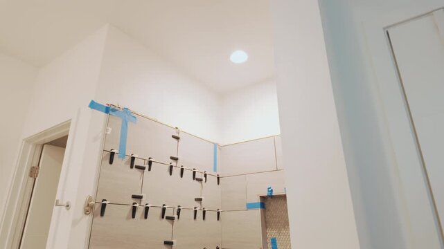 Handheld camera enters bathroom then tilts down across unfinished tiled shower