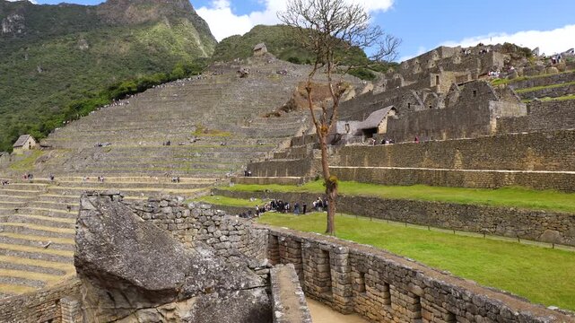 A view of the terraces and buildings of Machu Picchu. Tourists walk along the terraces of Machu Picchu.
