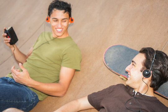 Two young friends listening music with cassette player and cd player - New trend people lifestyle using vintage analog devices - UGC flash content - Focus on right man face