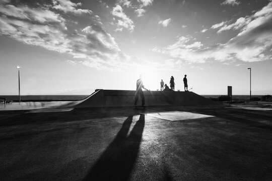 Young people having fun at skateboard park outdoor - Summer lifestyle and extreme sport concept - Soft focus on left guy face - Black and white film camera editing