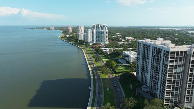 Top-down aerial of traffic flowing along Bayshore Boulevard in Tampa's Hyde Park, with the seawall promenade meeting the shimmering waters of Hillsborough Bay.