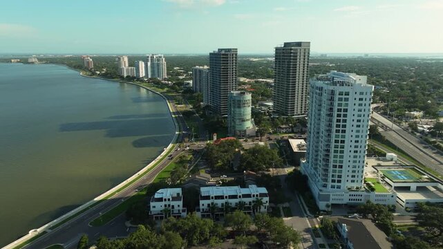 Drone shot of the tree-lined Bayshore Boulevard in Tampa, Florida, with modern high-rises meeting the sweeping curve of Hillsborough Bay.
