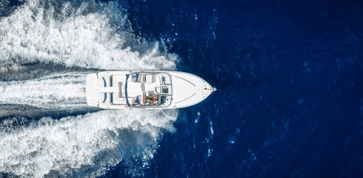 Aerial overhead view of a motorboat or yacht cruising with high speed over the ocean with copy space