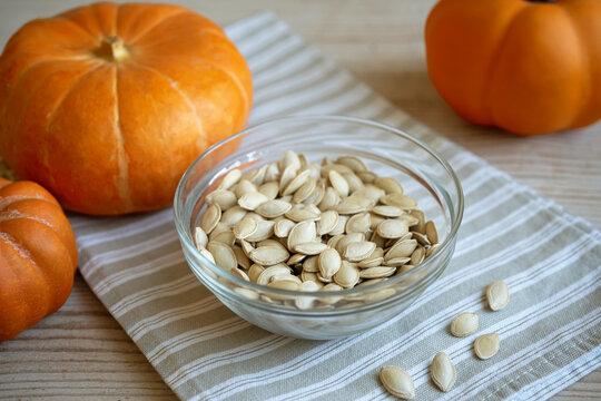 Bowl of raw pumpkin seeds and organic pumpkins