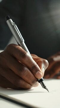 A Close-Up of a Hand Holding a Fountain Pen, Capturing the Artistry of Writing as Ink Flows onto Paper in a Brightly Lit Environment
