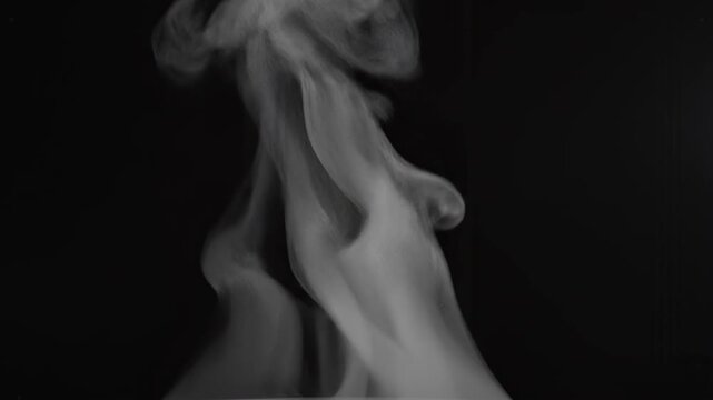 White smoke plume rising and expanding against a dark background with subtle lighting
