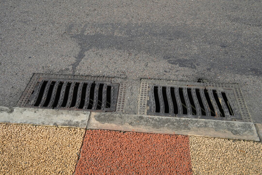 Metal drain grate on city sidewalk pavement,  jogging track