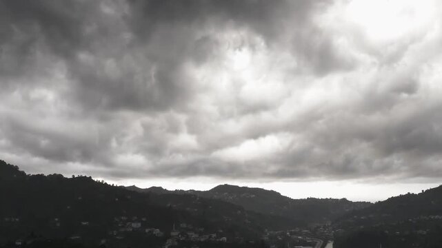 Ominous time lapse of dark, heavy storm clouds rolling over a silhouetted rural mountain village
