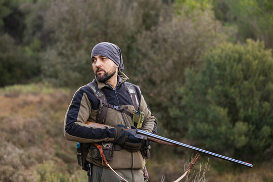 Hunter holding shotgun looking for game in forest