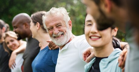 Fototapeta premium Diverse group of people smiling and standing arm in arm outdoors.