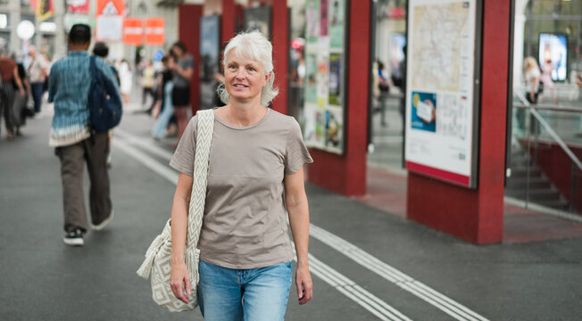 Caucasian senior woman walking at city metro station during evening time - Urban lifestyle concept - UGC content - Main focus on face