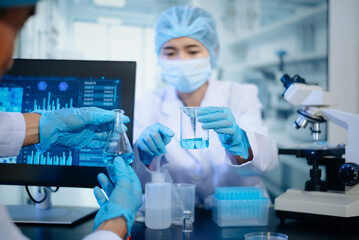 Fototapeta premium Two scientists in protective gear analyzing chemical samples in glass flasks in hightech research laboratory.