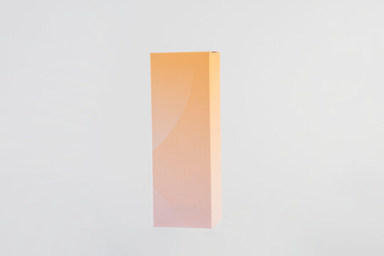 A small pink gift wrapping box and hand on white background.