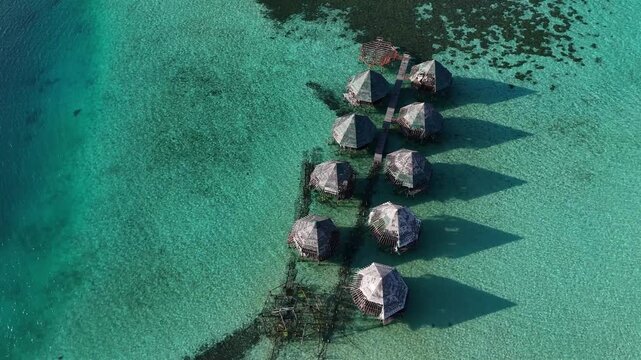 op Down Aerial Drone Shot of Abandoned Overwater Bungalows Casting Triangular Shadows on Turquoise Maldives Lagoon