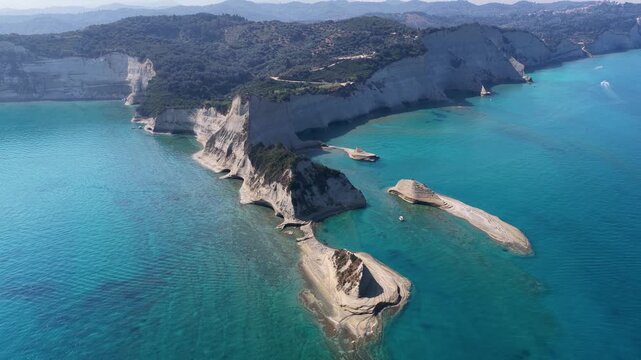 Aerial panoramic view of Cape Drastis cliffs and crystal clear turquoise sea in Corfu, Greece. Drone shot of dramatic white coastal rocks and blue water.