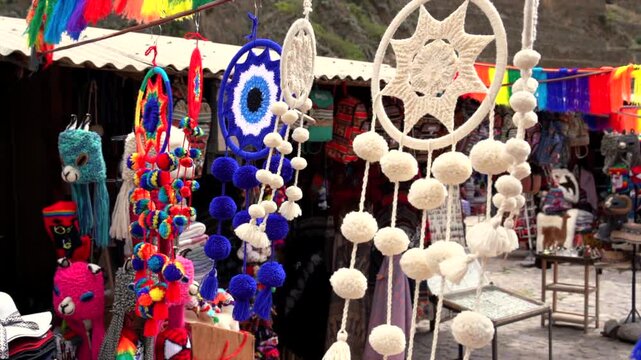 Slow motion video of handmade wool dreamcatchers and colorful Andean crafts swaying in the wind at a local souvenir market in Peru.