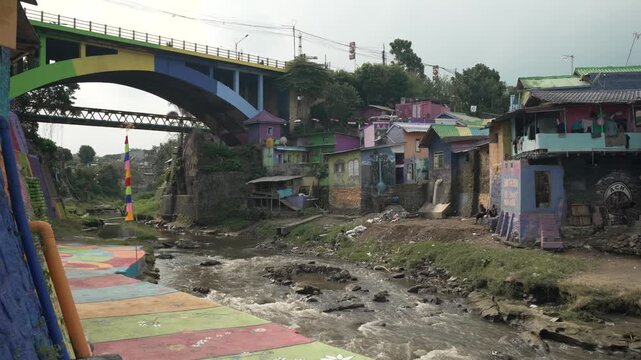 Historic Jembatan Buk Gluduk Crosses The Brantas River Beside Kampung Warna-Warni Jodipan In Malang, East Java, Indonesia. Wide Shot