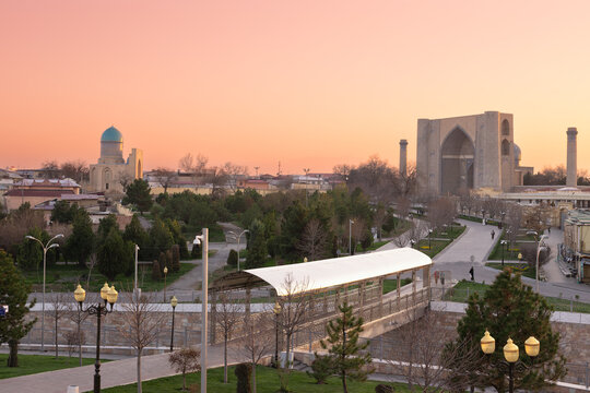 Bibi-Khanym Mosque panorama at sunset in Samarkand with parks and city rooftops under a pink sky. Historic Islamic landmark ideal for travel brochures and tourism publications.