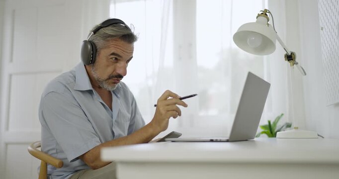 Portrait of happy caucasian business senior man casual cloths shirt work in home office desk using head phone computer. Small business employee freelance online sme marketing e-commerce telemarket