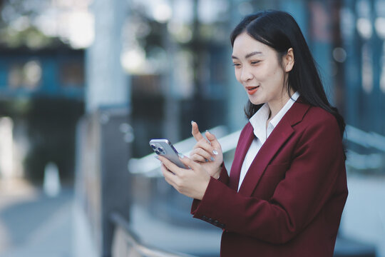 Young professional woman talking on phone and holding coffee outside modern office building