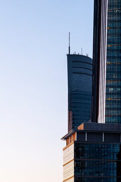 Skyscraper rises between urban buildings in Warsaw Poland with a narrow vertical composition and clear sky above the modern city skyline in an architecture view