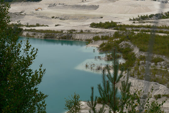 Turquoise lake in a working limestone quarry seen from the rim