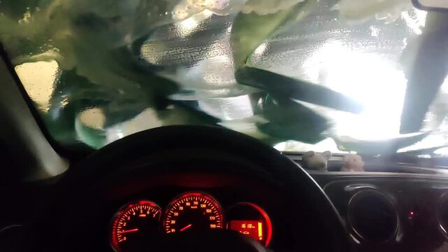 Car wash interior point of view showing soap patterns on the windshield from inside a moving vehicle.