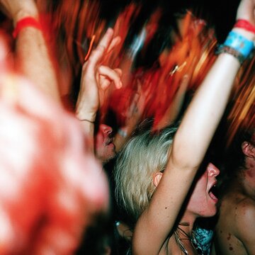 Excited young people cheering hands up at music concert