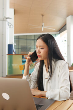 Stressed Businesswoman Talking on Smartphone While Working on Laptop Outdoors
