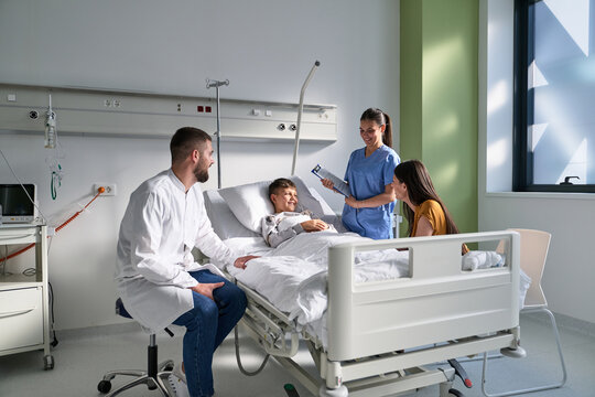 Caring medical staff interacting with smiling child in a bright hospital room