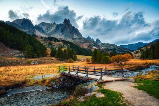 Rocky Mountain Peak with Bridge over River Surrounded by Larch Forest in Claree Valley French Alps Nevache France