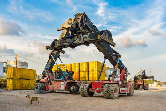 Reach stacker container handler lifting heavy cargo at shipping port freight yard outdoors