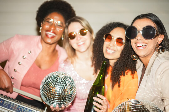 Group of multiracial girls dancing, drinking champagne and listening music outdoor - Party, summer and street nightlife concept - Main focus on right girl face - UGC flash content