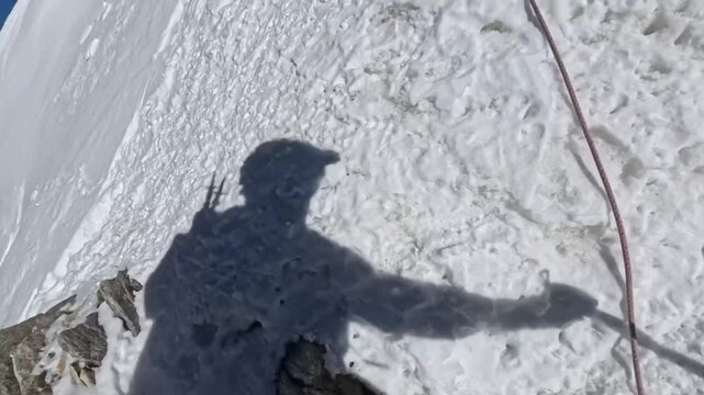 POV mountaineer climbing snowy ridge using rope and ice axe, alpine mountaineering adventure with hand and gear visible