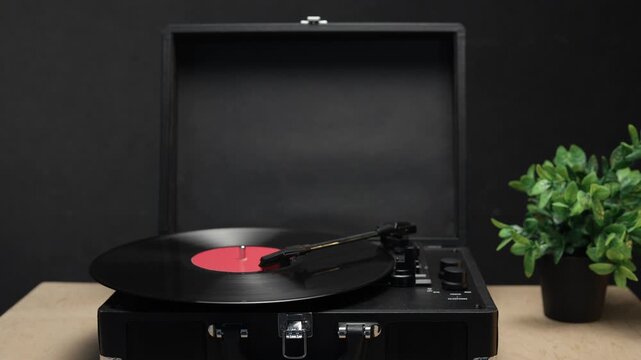 Vintage record player with vinyl disc spinning and plant in background