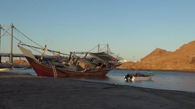 Traditional dhow boat and pedestrian suspension bridge in the harbor of Sur, Oman