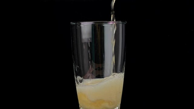 Beer pouring from bottle into glass with thick foam overflow.