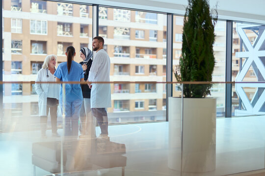 Healthcare professionals discuss patient care strategies in a modern hospital setting during a sunny day
