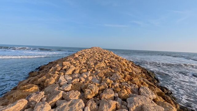 Stone breakwater jutting into the calm ocean waves