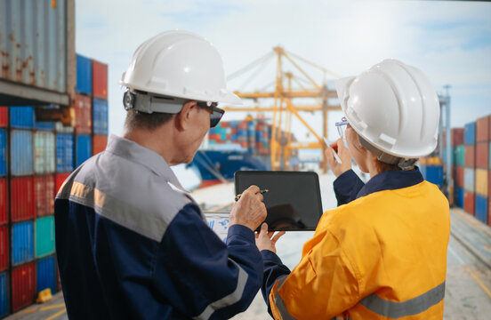 Engineers check cargo containers with a tablet at a busy shipping port, driving efficient global trade