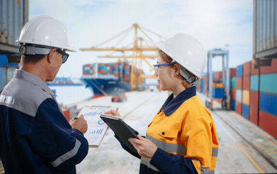 Engineers check cargo containers with a tablet at a busy shipping port, driving efficient global trade