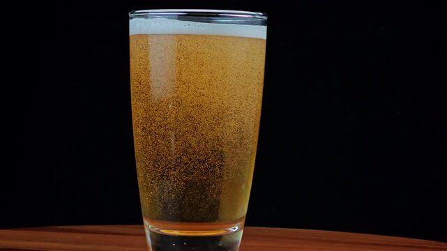 Beer pouring from bottle into glass with thick foam overflow.
