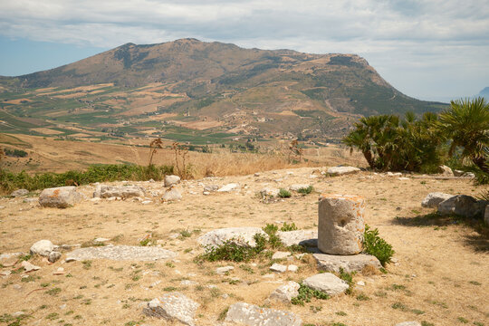 Ancient stone column fragment overlooking mountain landscape and countryside valley in Segesta, Sicily, Italy