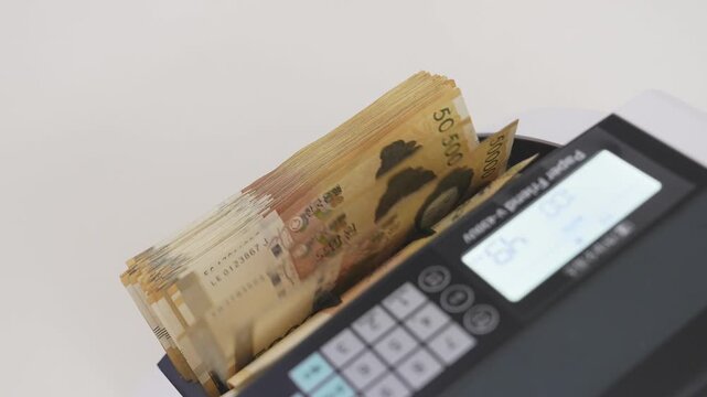 Close-up Fixed Shot of Money Counting Machine Counting 100 Crisp 50,000 Won Banknotes (Cash, Banking, Finance)